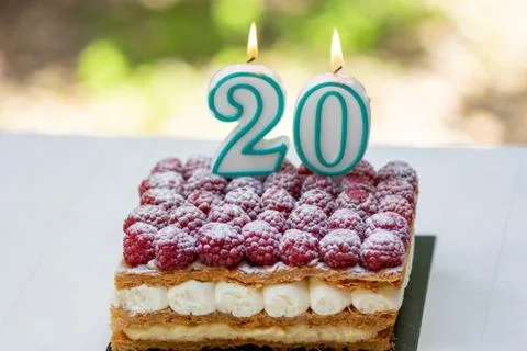 20th birthday raspberry cake with burning candles Stock Photos