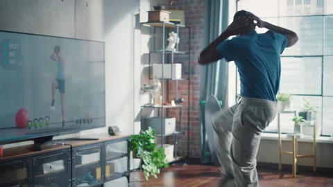 22 32 103 Man Energetically Exercising In Front Of TV Stock Footage 197419343
