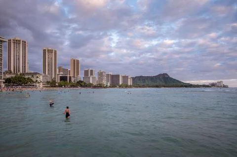 Honolulu,  Hawaii  -  December  29,  2022:  View  of  Waikiki  Beach  with  Diamond  Head  valcano  in  the  distance. xkwx architecture,  beach,  building  exterior,  city  life,  cityscape,  coastline,  diamond  head,  dusk,  famous  place,  hawaii,  hawaii  islands,  honolulu,  hotel,  island,  landscape  scenery,  mountain,  oahu,  ocean,  outdoors,  pacific  islands,  pacific  ocean,  panorama,  panoramic,  relaxation,  royal  hawaiian  hotel,  sand,  sea,  sky,  tourism,  tourist,  travel,  travel  destinations,  trees,  tropical,  tropical  climate,  twilight,  urban  skyline,  usa,  vacation,  waikiki,  waikiki  beach