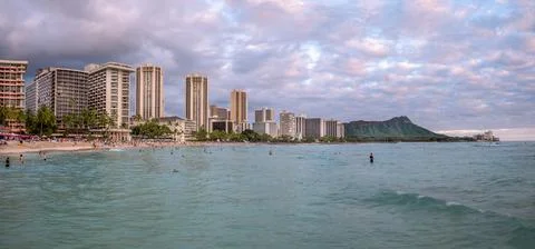 Honolulu,  Hawaii  -  December  29,  2022:  View  of  Waikiki  Beach  with  Diamond  Head  valcano  in  the  distance. xkwx architecture,  beach,  building  exterior,  city  life,  cityscape,  coastline,  diamond  head,  dusk,  famous  place,  hawaii,  hawaii  islands,  honolulu,  hotel,  island,  landscape  scenery,  mountain,  oahu,  ocean,  outdoors,  pacific  islands,  pacific  ocean,  panorama,  panoramic,  relaxation,  royal  hawaiian  hotel,  sand,  sea,  sky,  tourism,  tourist,  travel,  travel  destinations,  trees,  tropical,  tropical  climate,  twilight,  urban  skyline,  usa,  vacation,  waikiki,  waikiki  beach