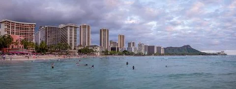 Honolulu,  Hawaii  -  December  29,  2022:  View  of  Waikiki  Beach  with  Diamond  Head  valcano  in  the  distance. xkwx architecture,  beach,  building  exterior,  city  life,  cityscape,  coastline,  diamond  head,  dusk,  famous  place,  hawaii,  hawaii  islands,  honolulu,  hotel,  island,  landscape  scenery,  mountain,  oahu,  ocean,  outdoors,  pacific  islands,  pacific  ocean,  panorama,  panoramic,  relaxation,  royal  hawaiian  hotel,  sand,  sea,  sky,  tourism,  tourist,  travel,  travel  destinations,  trees,  tropical,  tropical  climate,  twilight,  urban  skyline,  usa,  vacation,  waikiki,  waikiki  beach