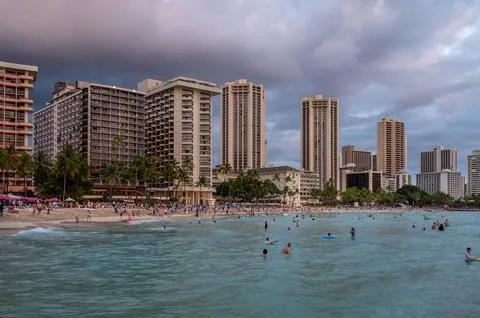 Honolulu,  Hawaii  -  December  29,  2022:  View  of  Waikiki  Beach  with  Diamond  Head  valcano  in  the  distance. xkwx architecture,  beach,  building  exterior,  city  life,  cityscape,  coastline,  diamond  head,  dusk,  famous  place,  hawaii,  hawaii  islands,  honolulu,  hotel,  island,  landscape  scenery,  mountain,  oahu,  ocean,  outdoors,  pacific  islands,  pacific  ocean,  panorama,  panoramic,  relaxation,  royal  hawaiian  hotel,  sand,  sea,  sky,  tourism,  tourist,  travel,  travel  destinations,  trees,  tropical,  tropical  climate,  twilight,  urban  skyline,  usa,  vacation,  waikiki,  waikiki  beach