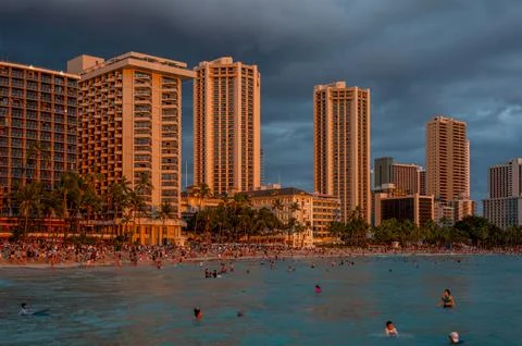 Honolulu,  Hawaii  -  December  29,  2022:  View  of  Waikiki  Beach  with  Diamond  Head  valcano  in  the  distance. xkwx architecture,  beach,  building  exterior,  city  life,  cityscape,  coastline,  diamond  head,  dusk,  famous  place,  hawaii,  hawaii  islands,  honolulu,  hotel,  island,  landscape  scenery,  mountain,  oahu,  ocean,  outdoors,  pacific  islands,  pacific  ocean,  panorama,  panoramic,  relaxation,  royal  hawaiian  hotel,  sand,  sea,  sky,  tourism,  tourist,  travel,  travel  destinations,  trees,  tropical,  tropical  climate,  twilight,  urban  skyline,  usa,  vacation,  waikiki,  waikiki  beach