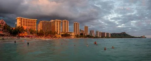 Honolulu,  Hawaii  -  December  29,  2022:  View  of  Waikiki  Beach  with  Diamond  Head  valcano  in  the  distance. xkwx architecture,  beach,  building  exterior,  city  life,  cityscape,  coastline,  diamond  head,  dusk,  famous  place,  hawaii,  hawaii  islands,  honolulu,  hotel,  island,  landscape  scenery,  mountain,  oahu,  ocean,  outdoors,  pacific  islands,  pacific  ocean,  panorama,  panoramic,  relaxation,  royal  hawaiian  hotel,  sand,  sea,  sky,  tourism,  tourist,  travel,  travel  destinations,  trees,  tropical,  tropical  climate,  twilight,  urban  skyline,  usa,  vacation,  waikiki,  waikiki  beach