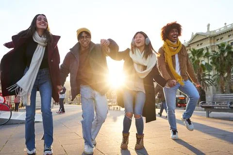 Group of multiracial friends having fun outdoors, walking holding hands and laughing at the city during winter time. xkwx group, people, young, happy, outdoor, student, life, team, fun, together, support, holiday, joy, school, couple, lifestyle, smile, beauty, freedom, row, season, cheerful, girl, hat, weekend, vacation, carefree, celebration, teenager, enjoyment, leisure, active, playful, friend, hold, hand, flare, walk, street, urban, gather, woman, man, city