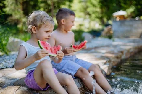 Little chidren sitting near a lake and eating watermelon on hot sunny day during summer vacation. xkwx happiness, watermelon, fruit, kid, happy, green, nature, red, food, fun, picnic, healthy, outdoor, joy, health, juicy, eat, girl, childhood, slice, boy, nutrition, cute, sweet, smile, little, eating, cheerful, snack, summertime, caucasian, meal, enjoy, outside, melon, garden, water, delicious, friend, refreshment, holiday, brother, sister, freshness, warm, preschool, siblings