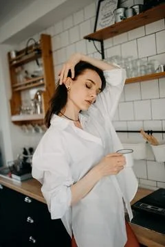 Beautiful woman drinking coffee in her vintage kitchen. xkwx beautiful woman, lifestyle, white shirt, coffee, kitchen, indoors, red tights, relaxing, wall, vintage, retro, desk, kitchen table, cup, morning, home, house, sensual, beautiful, standing, Å½drelo, BraniÄevo District, Serbia, Thirties, Generation X, 36-39 Years Old, One Person, Female, White