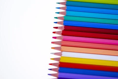 24 multicolored crayons on a white background, neatly arranged and sharpened. Stock Photos