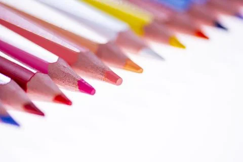 24 multicolored crayons on a white background, neatly arranged and sharpened. Stock Photos