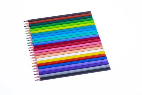 24 multicolored crayons on a white background, neatly arranged and sharpened. Stock Photos
