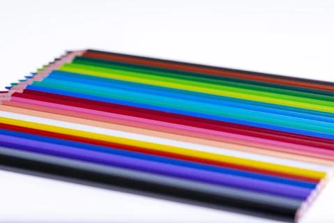 24 multicolored crayons on a white background, neatly arranged and sharpened. Stock Photos