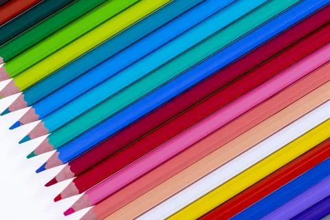 24 multicolored crayons on a white background, neatly arranged and sharpened. Stock Photos