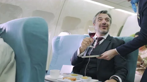 2400 1 Flight attendance serve wine to passenger in first class of airplane. Stock Footage 146905997