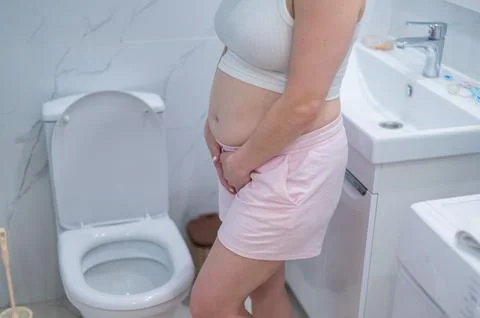 Pregnant woman holding her belly in the toilet. incontinence during pregnancy xkwx pregnant woman holding belly toilet incontinence during pregnancy pain care bathroom birth ache bladder childbirth constipation expecting fatigue hands cramp crotch control health healthcare hurt hurrying hygiene indigestion infection labor maternity mom mother pee pressure restroom problem rushing stomach suffer urgent urination weak home body symptom bad tummy
