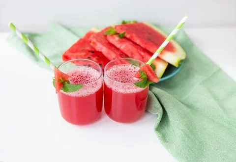 Juicy freshly squeezed watermelon juice in a glass along with a green tube, against a green napkin xkwx watermelon glass juice juicy slice smoothie sweet mint drink tube organic healthy napkin summer seeds cold cocktail red refreshment green fruit fresh summertime diet freshness food white table ice close up delicious crushed nobody liquid detox gourmet appetizing mixed vitamin natural shake blender tropical leaf vegetarian nutritious ripe tasty serving