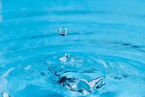 Close up of water drop falling into water with ripples and copy space on blue background. Water, liquid and colour concept. xkwx No People Close Water Drop Falling Water Ripple Copy Space Blue Background Liquid Colour Concept Drop Splash Abstract Design Background Wet Flow Fluid Closeup Wave Illustration Macro Business Graphic Symbol Isolated Flowing Color Clean Drink Water Falling Copy Space Blue