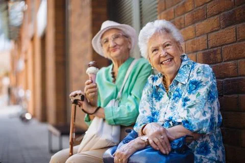 Portrait of two senior female friends in the city, eating ice cream on a hot summer day. Elderly ladies on summer vacation in the city. Pensioners on group trip. Concept of senior vacation and travel groups, clubs. xkwx senior city ice cream woman retirement pensioner lifestyle active outdoor elderly old joy vitality happiness smiling eating street togetherness trendy happy holding tourist cone community bonding enjoyment lady older brick wall sitting travel group travel club senior travel traveling vacation chronic illness diabetes heart disease alzheimers disease mental health osteoporosis arthritis dementia hypertension cholesterol depresion rheumatoid arthritis incontinence