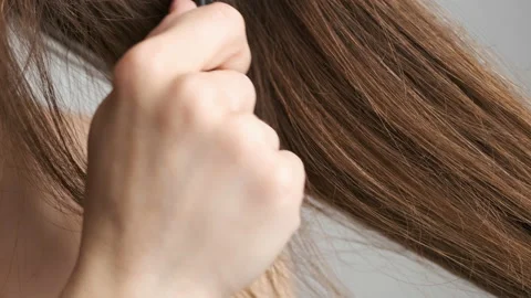 A 25-year-old brunette stands in the bathroom in front of a mirror and combs her Video stock 132838517