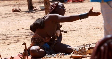 25.01.2020, Kunene, Namibia, Himba tribe woman is sitting on the ground, 4k Stock Footage 129361829