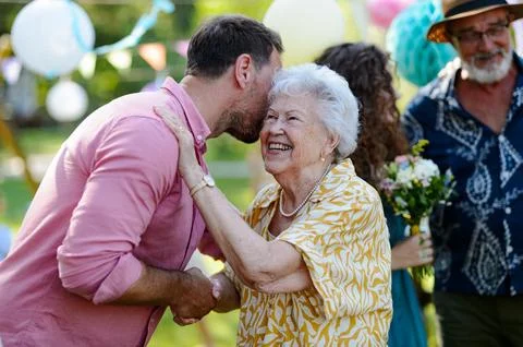 Garden birthday party for senior lady. Beautiful senior birthday woman receiving birthday wishes. xkwx birthday woman senior hugging gifts garden birthday party beautiful woman lady receiving gift wishes embrace smile friends family grandmother grandson celebration joy happiness presents outdoors event festivity gathering special occasion surprise smiles enjoyment togetherness love affection decorations cake memories balloons laughter congratulations entertainment bonding delight cheerful atmosphere friendship gratitude copy space gray hair pearls