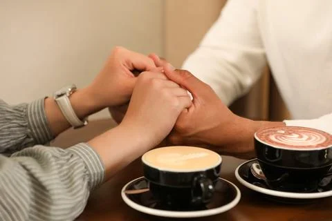 Romantic date. Couple holding hands together in cafe, closeup xkwx adult background biracial bonding boyfriend cafe cappuccino casual closeup coffee couple cups date dating drink enjoying enjoyment feelings female flirt girlfriend guy hands happiness holding indoors latte lifestyle love lovely lover lovers male man meeting mixed multiracial people relationships romance romantic spending sweetheart table time together togetherness woman young