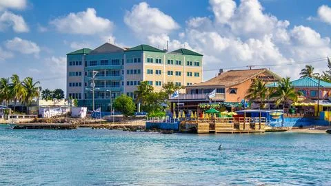 Grand Cayman - March 3, 2012: Buildings of Grand Cayman in the morning along the coastline. xkwx caribbean people travel building architecture colorful blue tropical nature caribbean tourism outdoor sky tourist town beach wooden ocean sand water grand tree cayman wood vacation beautiful sea landmark landscape coast sunny bay holiday leisure island fence palm house cayman islands street exterior view