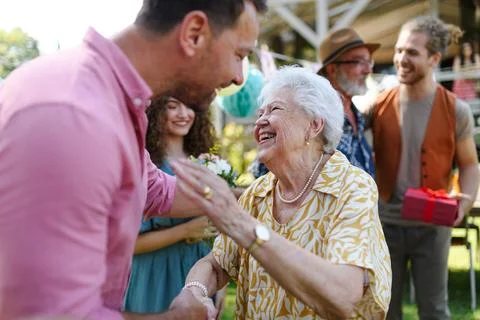 Garden birthday party for senior lady. Beautiful senior birthday woman receiving birthday wishes and gifts. xkwx birthday woman senior hugging gifts garden birthday party beautiful woman lady receiving gift wishes embrace smile friends family grandmother grandson celebration joy happiness presents outdoors event festivity gathering special occasion surprise smiles enjoyment togetherness love affection decorations cake memories balloons laughter congratulations entertainment bonding delight cheerful atmosphere friendship gratitude copy space gray hair pearls