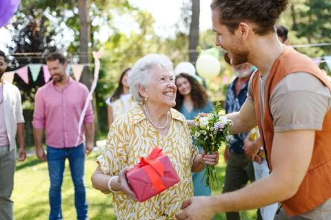 Garden birthday party for senior lady. Beautiful senior birthday woman receiving birthday wishes and gifts. xkwx birthday woman senior hugging gifts garden birthday party beautiful woman lady receiving gift wishes embrace smile friends family grandmother grandson celebration joy happiness presents outdoors event festivity gathering special occasion surprise smiles enjoyment togetherness love affection decorations cake memories balloons laughter congratulations entertainment bonding delight cheerful atmosphere friendship gratitude copy space gray hair pearls