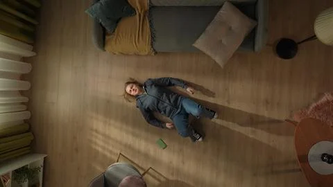 Top view of a young woman lying on the living room floor next to a smartphone. The woman is hysterical, kicking her feet and hands on the floor, after losing an online game. Gadget addiction xkwx mental health woman overhead depressed top view addiction living room crisis floor dependent hand sad problem smartphone technology phone communication mobile connection alone internet emotion online distressed frustration upset game result losing disappointment amazed chagrin expression lying hysterics beating feet negatively frustrated indoor apartment home lifestyle young adult person