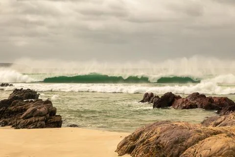 260327 8946 A breaking wave throws up wind blown sea spray. Stock Photos