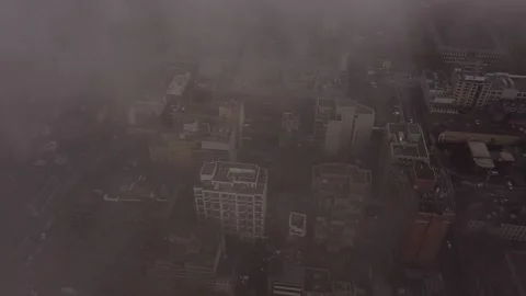 2.7K aerial flight looking down at buildings and street through thick haze and t Stock Footage 149896899