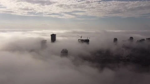 2.7K aerial flight over dense moving fog with buildings popping through the fog  Stock Footage 149896880