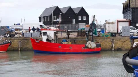 28 October 2020 - Whitstable UK: Small red fishing boat in calm harbour Stock Photos