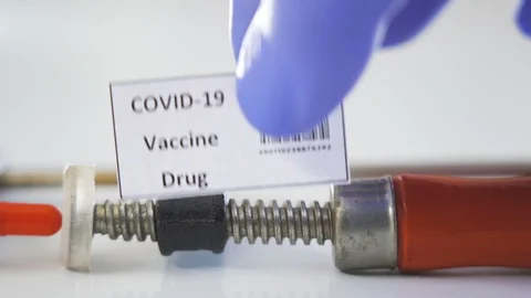 29105 The red capsule in the clamp with the sign of coronavirus or Covid-19 v Stock Footage 129337581