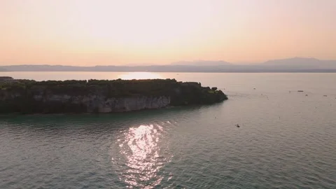 Sun setting behind Simo Peninsula, Sirmione, Lake Garda, Italy - Aerial Drone Sun setting behind Simo Peninsula, Sirmione, Lake Garda, Italy - Aerial Drone