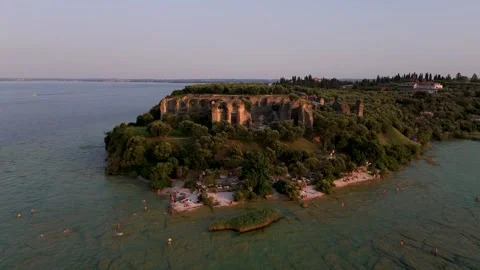 Pan back from small beach at sunset, Sirmione, Lake Garda, Italy - Aerial Drone Pan back from small beach at sunset, Sirmione, Lake Garda, Italy - Aerial Drone