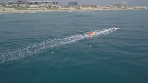 2K Aerial Drone Side View of Jet Ski riding inflatable banana boat in ocean Stock Footage 128029105