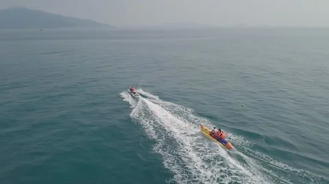 2K Aerial Drone Top Down View of Jet Ski riding inflatable banana boat in ocean Stock Footage 128029590