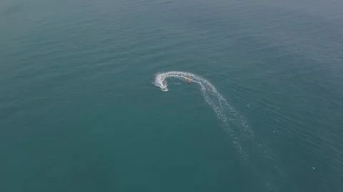 2K Aerial Top Down View of Jet Ski riding inflatable banana boat in green sea Stock Footage 128029978