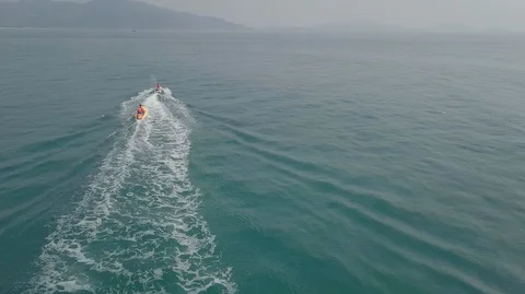 2K Aerial View of Jet Ski riding inflatable banana boat in green sea. Water Stock Footage 128029543