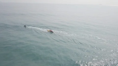 2K Aerial View of Jet Ski riding inflatable banana boat in green sea. Water Stock Footage 128029700