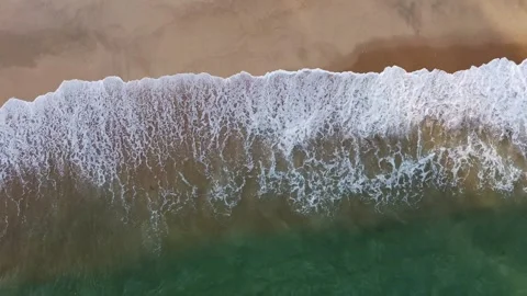 2K Drone top down static shot of ocean waves crashing on a sandy beach. 動画素材 336864574