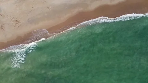 2K Drone top down view tracking slowly along the coastline as waves 動画素材 336864568