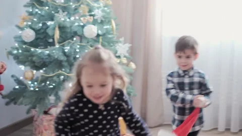 3 authentic happy Joy children wave hands hello rejoice by Christmas tree play Stock Footage 153822448