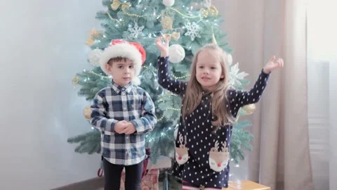 3 authentic happy Joy children wave hands hello rejoice by Christmas tree play Video stock 154146358