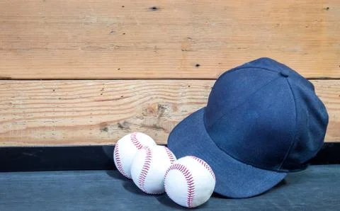 3 baseballs and a baseball cap in front of a wooden wall Stock Photos