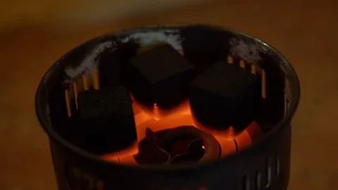 3 black square coals cook and blush from the hot temperature on a red-hot spiral Stock Footage 125456174