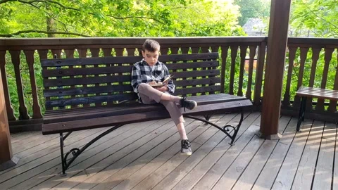 3 boy sitting on a bench and reading books in the summer Stock Footage 265758276