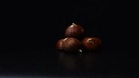 3 chestnuts rotating in front of a black background Stock Footage 238861369