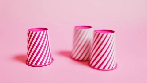 3 Cups and a ball game. Guess where a ball is. Pink background. Front view Stock Footage 201172248